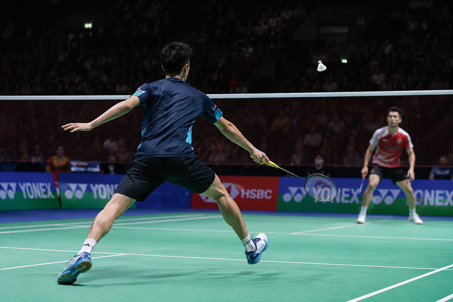 Player lunging across a badminton singles court during a competitive rally, demonstrating court movement, positioning, and shot strategy.